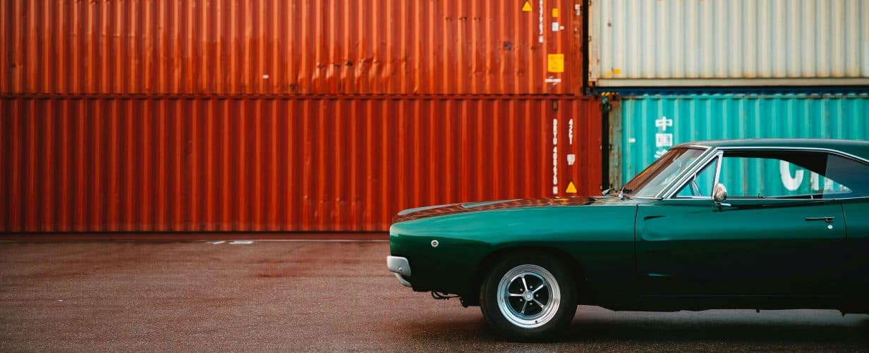A vintage car near shipping containers